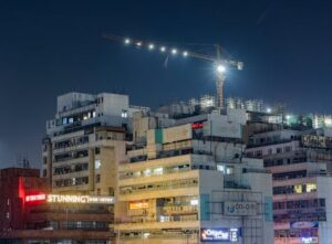 A vibrant nighttime view of high-rise buildings and crane in New Delhi, India.