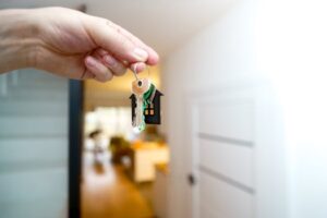A hand holding house keys inside a modern apartment, symbolizing new property ownership or rental.